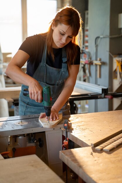 Mittlere Schussfrau, die mit Bohrmaschine arbeitet