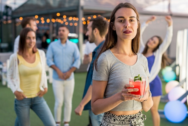 Kostenloses Foto mittlere schussfrau, die mit einem cocktail aufwirft