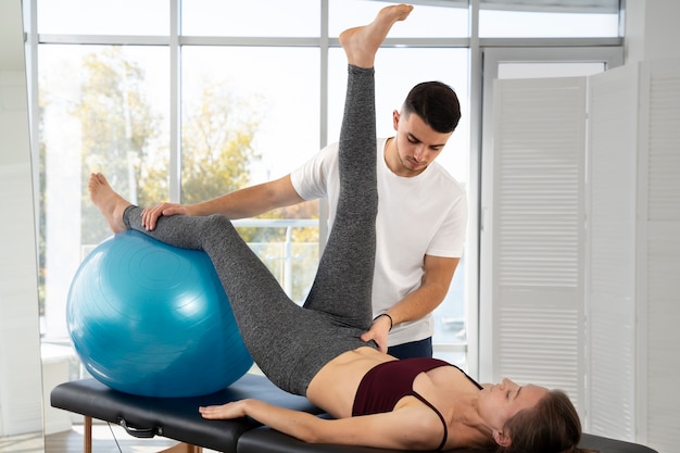 Mittlere Schussfrau, die mit Gymnastikball trainiert