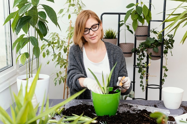 Mittlere Schussfrau, die mit Handschuhen im Garten arbeitet