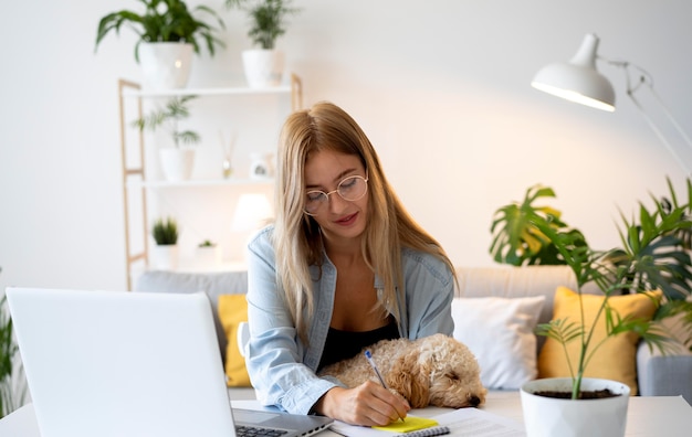 Mittlere Schussfrau, die mit Hund zuhause arbeitet