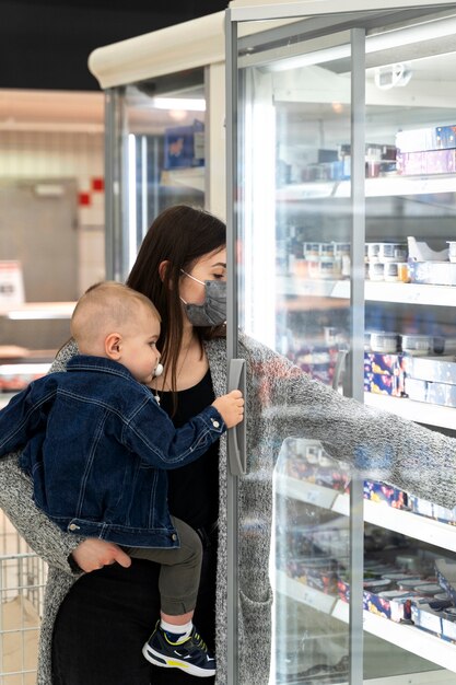 Mittlere Schussfrau, die mit Kind einkauft