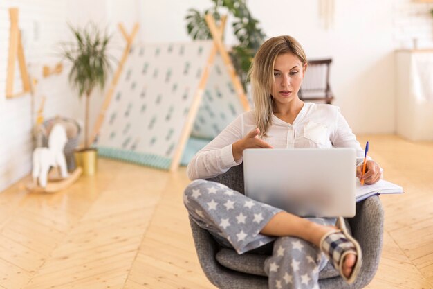 Mittlere Schussfrau, die mit Laptop arbeitet