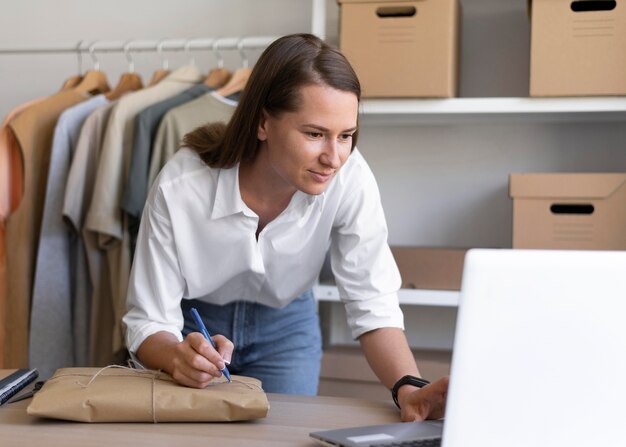 Mittlere Schussfrau, die mit Laptop arbeitet