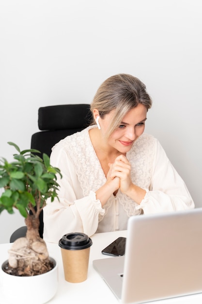 Kostenloses Foto mittlere schussfrau, die mit laptop arbeitet