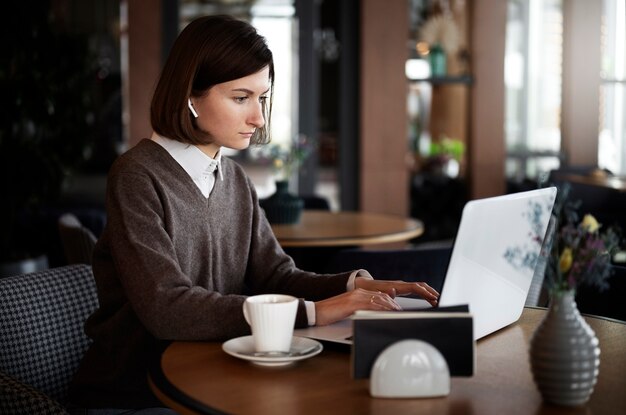 Mittlere Schussfrau, die mit Laptop arbeitet