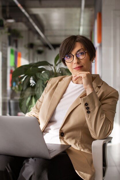 Mittlere Schussfrau, die mit Laptop arbeitet