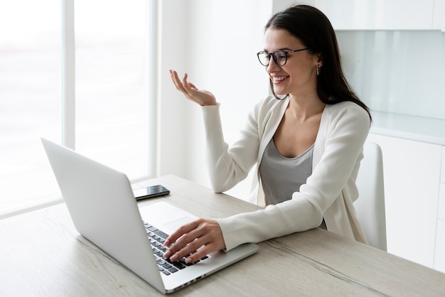 Mittlere Schussfrau, die mit Laptop zu Hause arbeitet