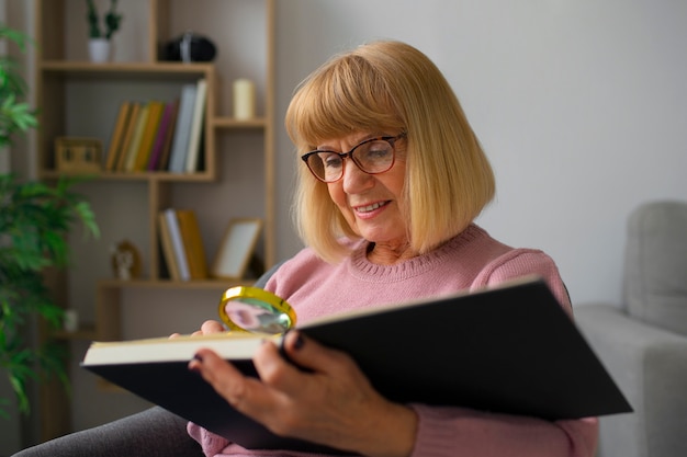 Kostenloses Foto mittlere schussfrau, die mit magnyfier liest