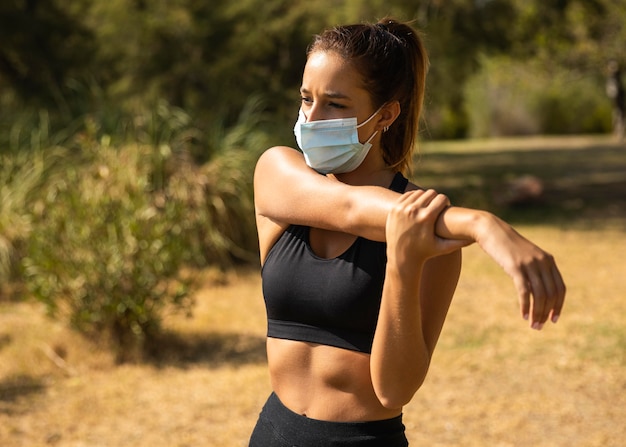 Kostenloses Foto mittlere schussfrau, die mit maske streckt