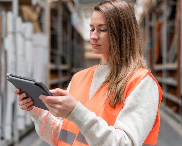 Mittlere schussfrau, die mit tablette arbeitet