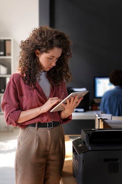 Mittlere Schussfrau, die mit Tablette arbeitet