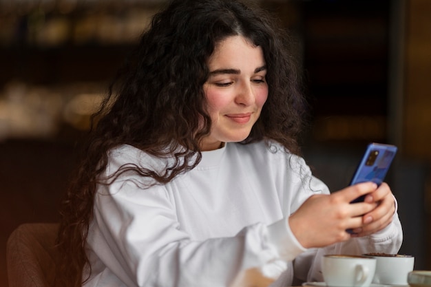 Mittlere Schussfrau, die Smartphone hält