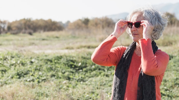 Kostenloses Foto mittlere schussfrau, die sonnenbrille aufsetzt