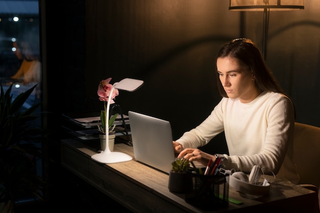 Kostenloses Foto mittlere schussfrau, die spät nachts arbeitet