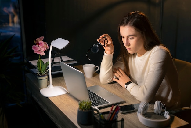 Kostenloses Foto mittlere schussfrau, die spät nachts arbeitet