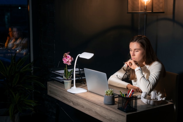 Kostenloses Foto mittlere schussfrau, die spät nachts arbeitet