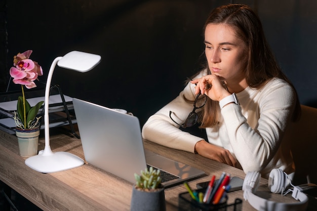 Kostenloses Foto mittlere schussfrau, die spät nachts arbeitet