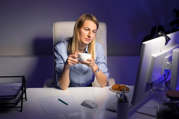 Kostenloses Foto mittlere schussfrau, die spät nachts arbeitet