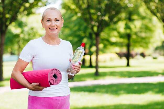 Mittlere Schussfrau, die Yogamatte hält