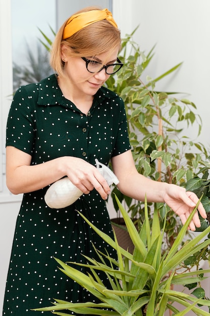 Kostenloses Foto mittlere schussfrau, die zimmerpflanze wässert