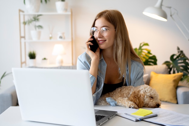 Mittlere Schussfrau, die zu Hause mit Hund arbeitet