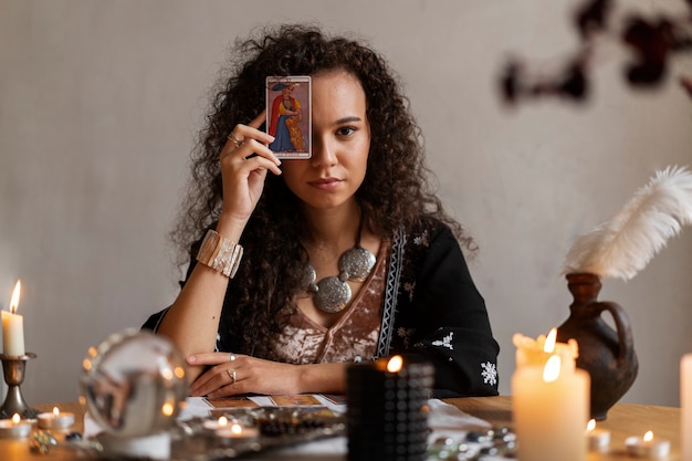 Kostenloses Foto mittlere schussfrau, die zu hause tarot liest