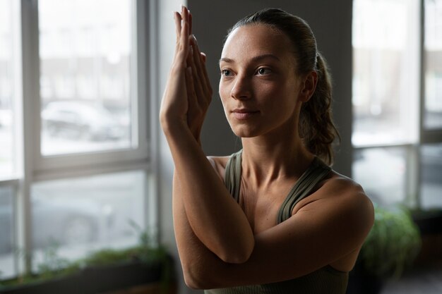 Mittlere Schussfrau, die zuhause Yoga tut