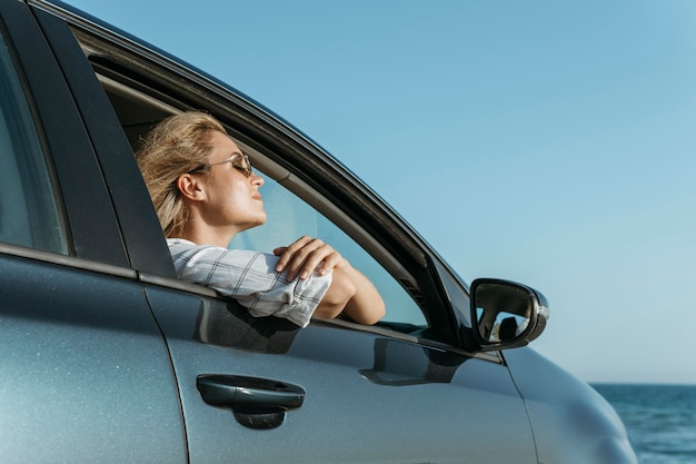 Mittlere Schussfrau im Auto, das Meer betrachtet