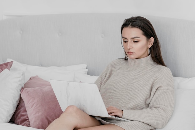 Mittlere Schussfrau im Bett mit Laptop