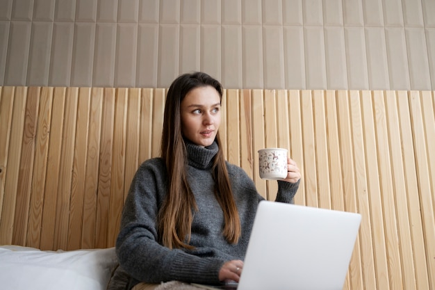 Kostenloses Foto mittlere schussfrau im bett mit laptop