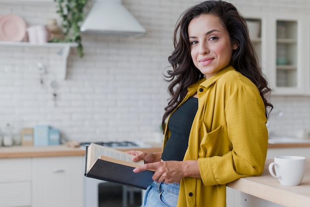 Mittlere Schussfrau mit Buch in der Küche