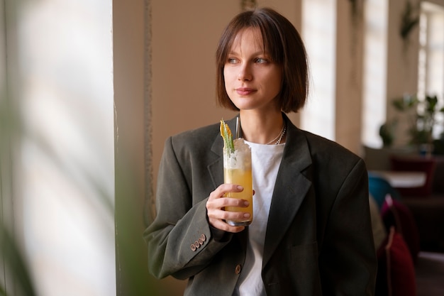 Kostenloses Foto mittlere schussfrau mit köstlichem cocktail