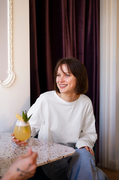 Kostenloses Foto mittlere schussfrau mit köstlichem cocktail