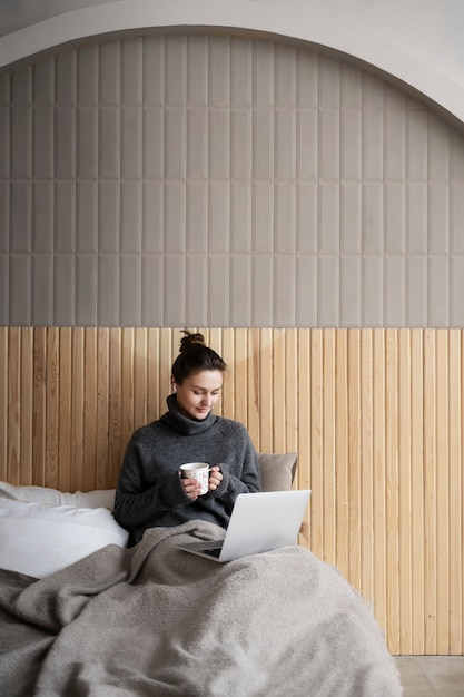 Mittlere schussfrau mit laptop im bett