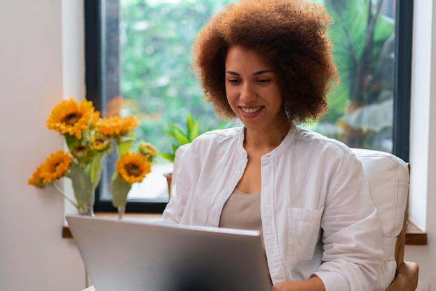 Kostenloses Foto mittlere schussfrau mit laptop und sonnenblumen