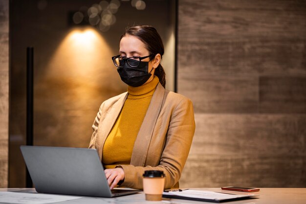 Mittlere Schussfrau mit Maske und Laptop