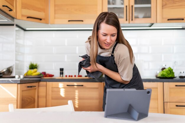 Mittlere Schussfrau mit Tablette in der Küche