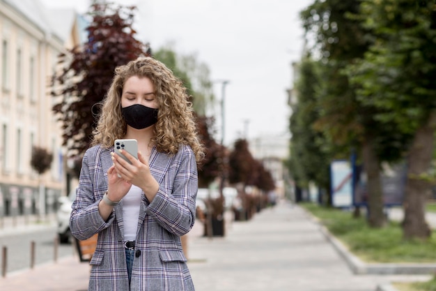 Kostenloses Foto mittlere schussfrau mit telefon im freien