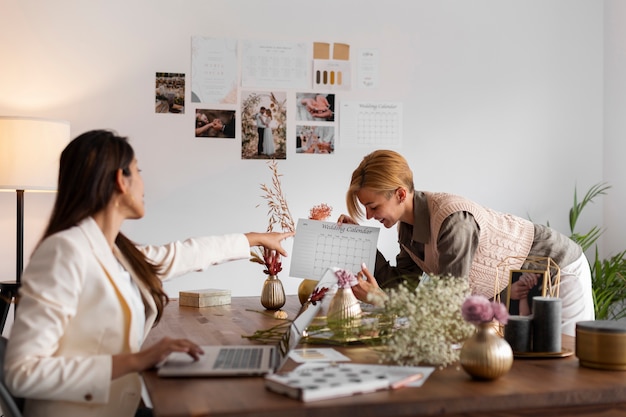 Kostenloses Foto mittlere schussfrauen, die als hochzeitsplaner arbeiten