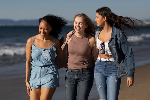 Kostenloses Foto mittlere schussfrauen, die am strand gehen