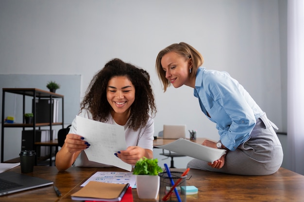 Kostenloses Foto mittlere schussfrauen, die im büro zusammenarbeiten