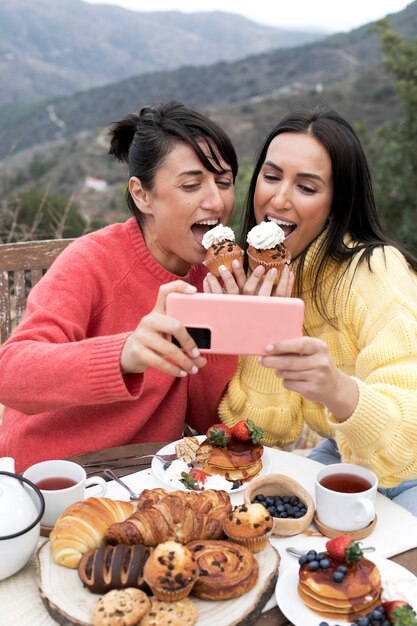 Mittlere schussfrauen, die kleine kuchen essen