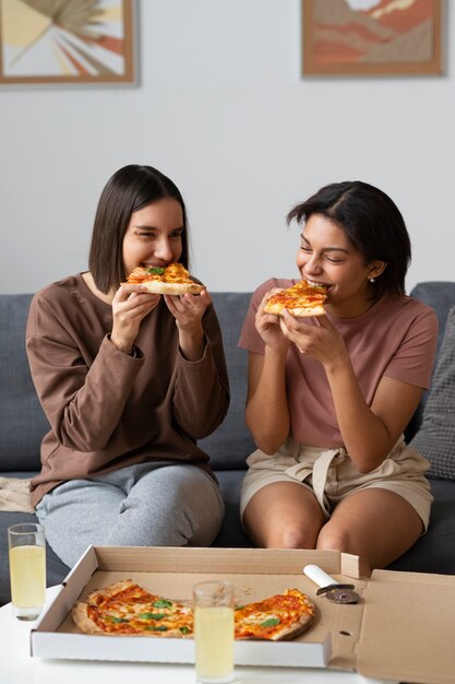 Mittlere Schussfrauen, die köstliche Pizza essen