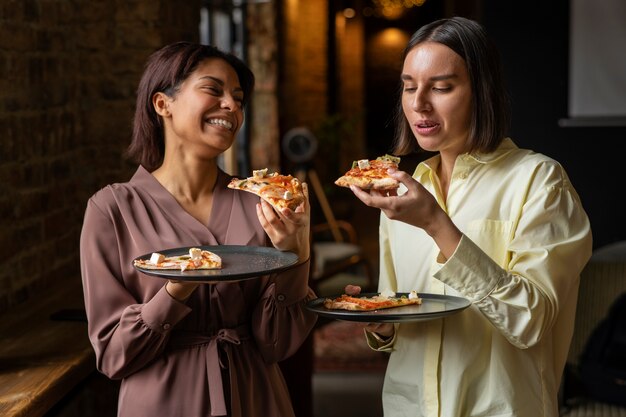 Mittlere Schussfrauen, die köstliche Pizza essen