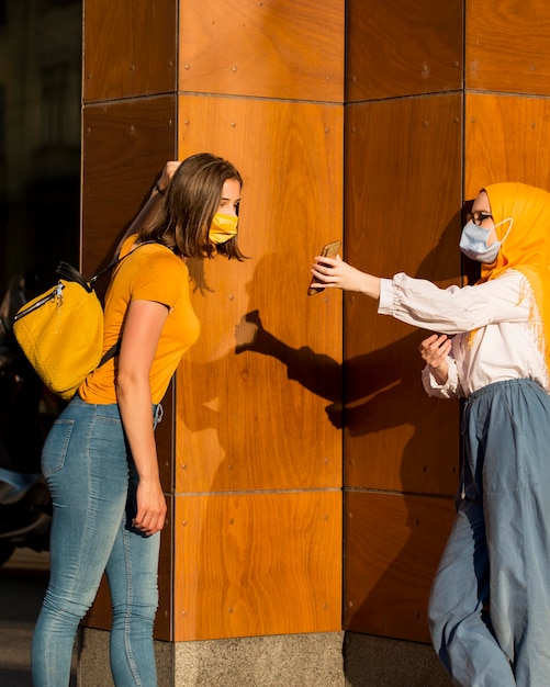 Mittlere Schussfrauen, die Masken tragen