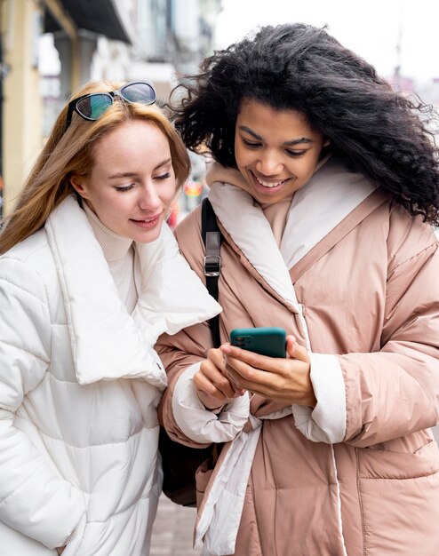 Mittlere Schussfrauen, die Smartphone betrachten