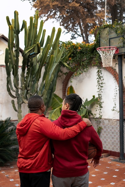 Kostenloses Foto mittlere schussfreunde, die draußen basketball spielen