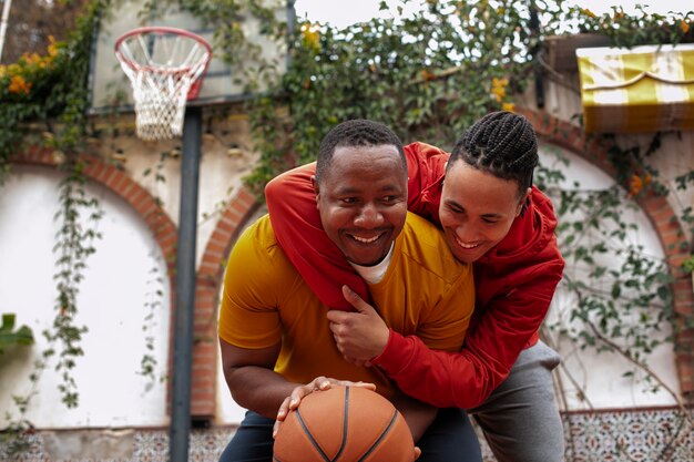 Mittlere Schussfreunde, die draußen Basketball spielen