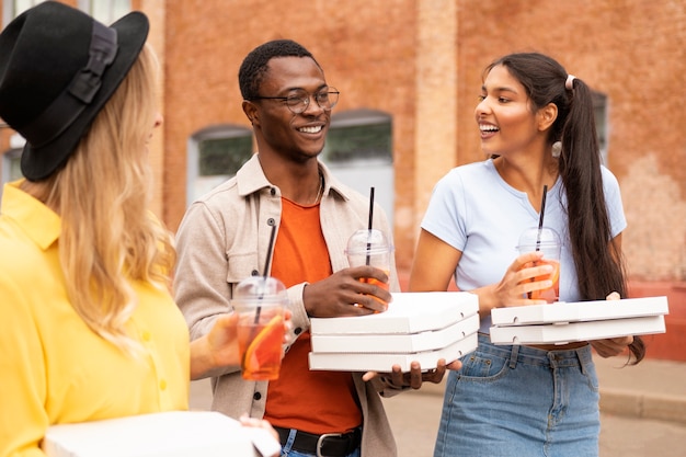 Kostenloses Foto mittlere schussfreunde mit pizza draußen